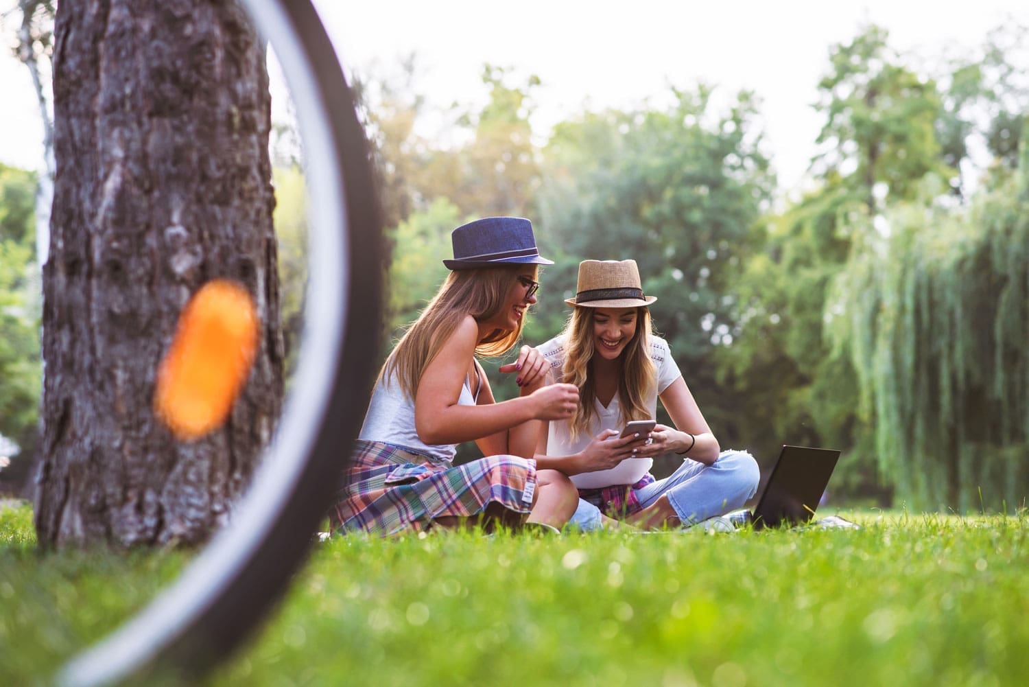 Two female friends sitting on the grace talking and using tablet iPad.